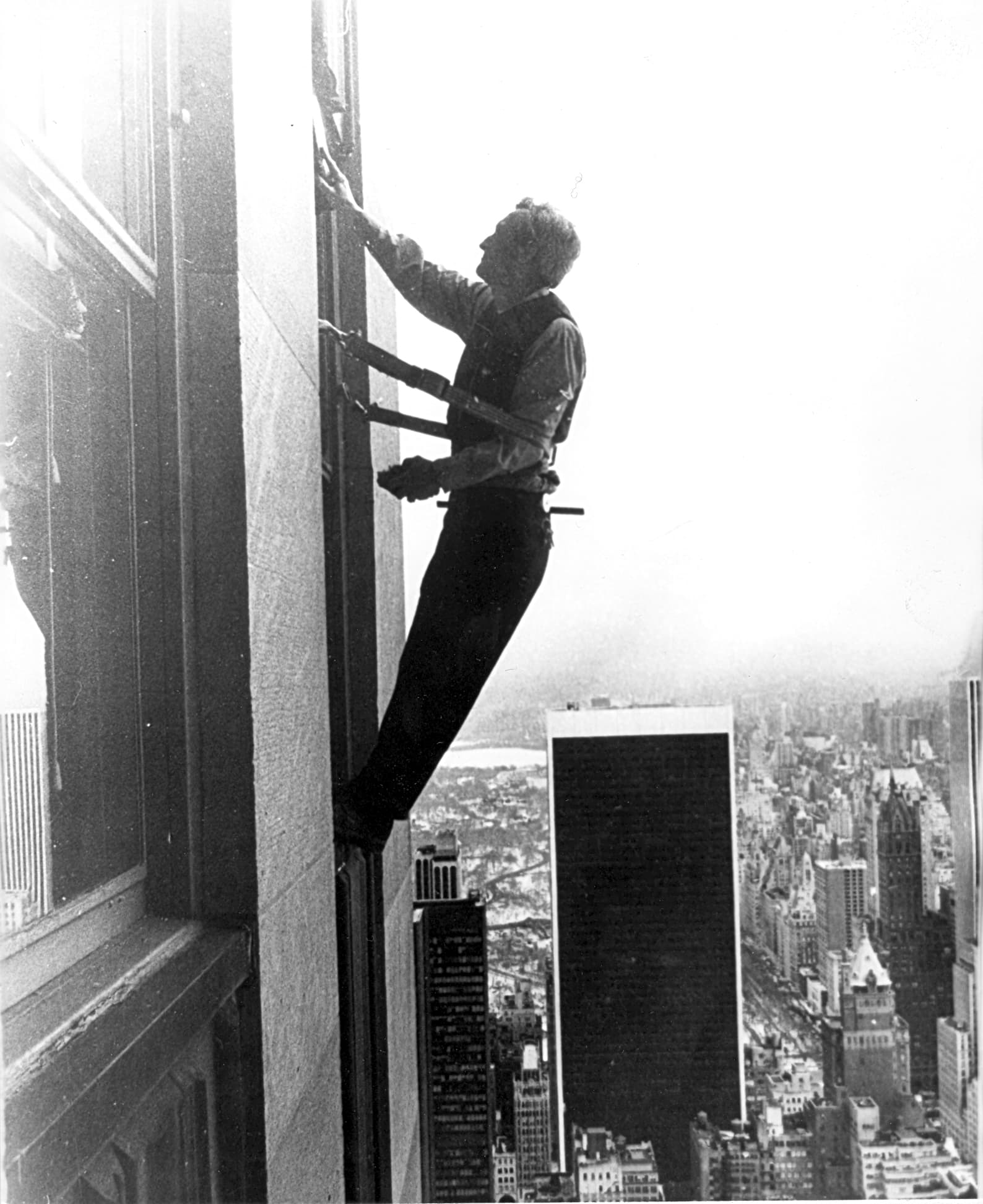 A window cleaner in a harness working high up on a New York skyscraper